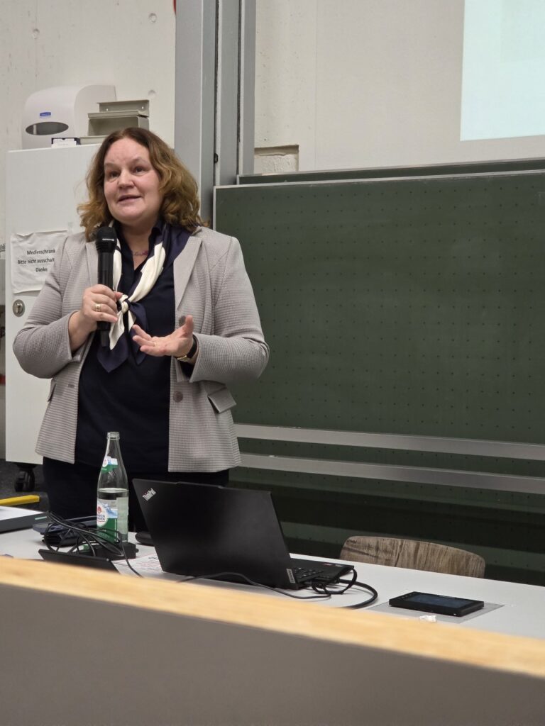 Daniela Schackis presenting in front of a chalkboard.